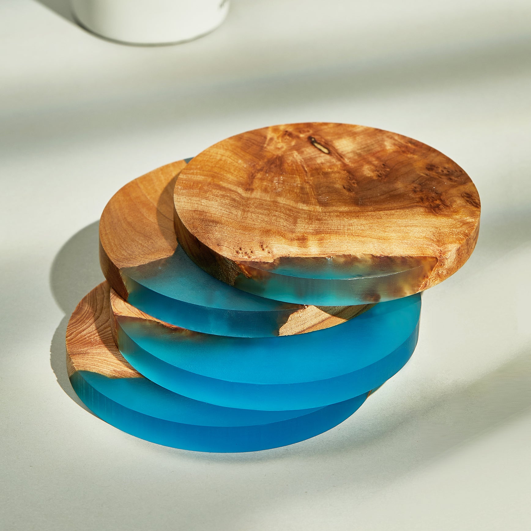 Set of 4 wood and epoxy resin coasters displayed on a modern kitchen counter